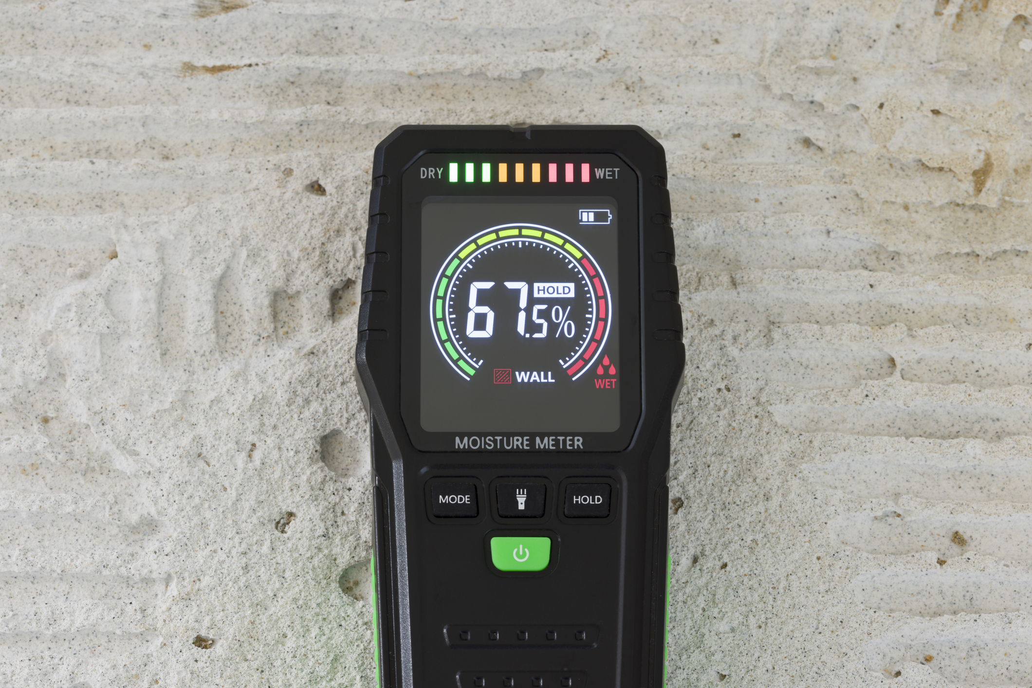 Moisture meter showing a high wet reading on a wall during a water damage inspection